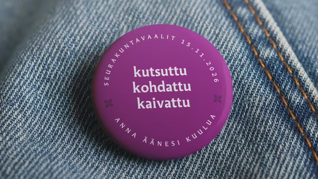farkkukankaaseen kiinnitetty lila rintanappi kutsuttu kohdattu kaivattu tekstillä
